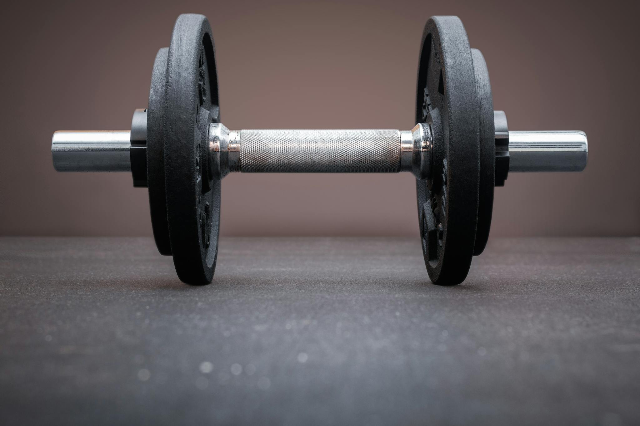 A single dumbbell resting on a gym floor symbolizes strength and fitness.